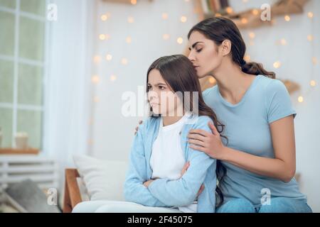 Offeso guardando via la ragazza e abbracciando la madre premurosa Foto Stock