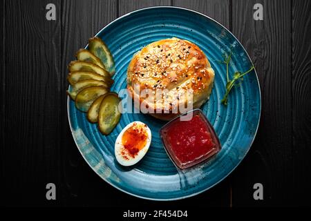 elesh con carne e semi di sesamo, su un piatto, su una tavola nera, con salsa e sottaceti Foto Stock