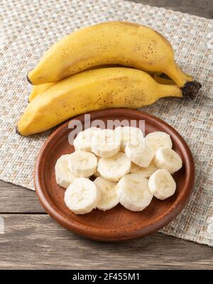 Banane e fette su un piatto su un tavolo di legno. Foto Stock