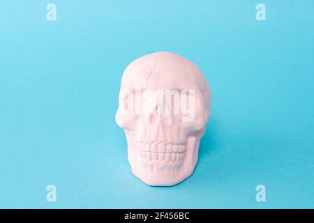 Cranio rosa su sfondo blu pastello. Concetto di spooky minimo di Halloween. Foto Stock