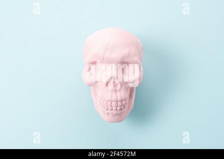Cranio rosa su sfondo blu pastello. Concetto di spooky minimo di Halloween. Foto Stock