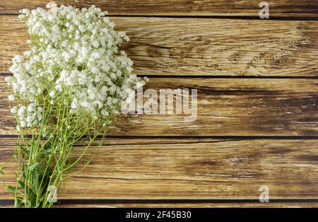 Bouquet di fiori bianchi minuscoli su tavolo di legno. Foto Stock