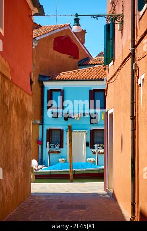 Piccola via di canale sull'isola di Burano a Venezia. Paesaggio urbano veneziano Foto Stock