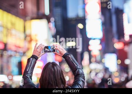 una donna che scatta una foto nella città di new york Foto Stock