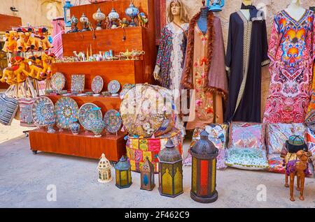 I diversi beni del negozio turistico (abbigliamento, ceramiche, lampade, cuscini, giocattoli) nella strada del mercato al Fahidi, Dubai, Emirati Arabi Uniti Foto Stock