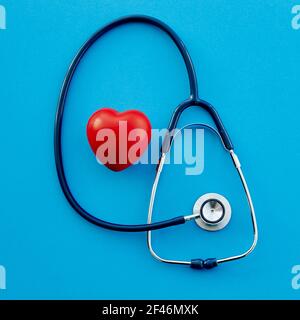 stetoscopio e cuore rosso su sfondo blu. Foto Stock