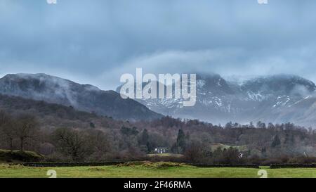 Splendida vista panoramica da Elterwater in direzione di Langdale La catena montuosa Pikes sulla nebbia mattina invernale Foto Stock