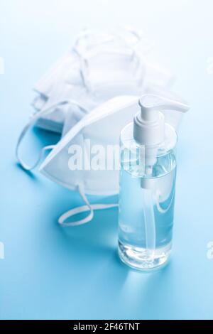 Disinfettante per le mani per la prevenzione del coronavirus e maschera respiratore Kn95. Gel disinfettante per le mani nel flacone della pompa sul tavolo blu. Foto Stock