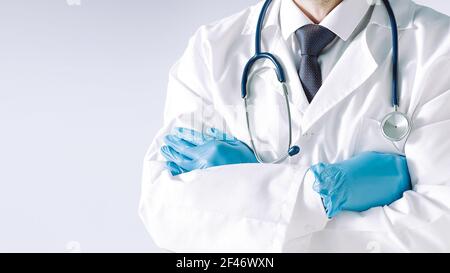 il medico che indossa una maschera protettiva e guanti ti guarda con sicurezza. Foto Stock