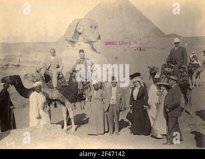 Giza (Egitto). Turisti e leader indigeni con cammelli di fronte alla Sfinge e le piramidi di Giza Foto Stock