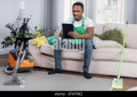 Detergente africano con tablet digitale mentre ci si rilassa sul divano Foto Stock