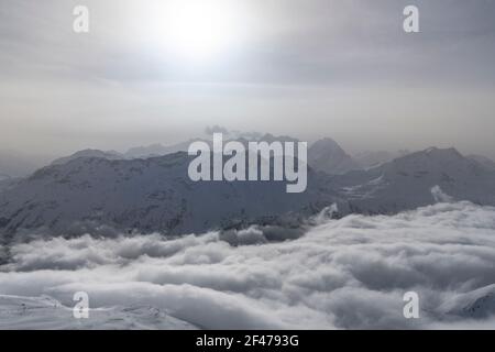 Luce del sole sulle montagne innevate nella nebbia mattutina, cantone di Graubunden, alta Engadina, Svizzera Foto Stock