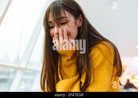 Affascinante eccitata bella ragazza che copre la sua bocca mentre esprime sorpresa all'interno Foto Stock