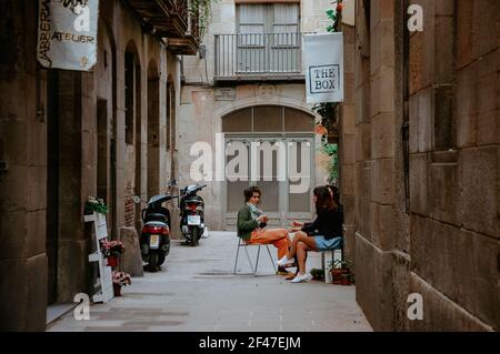 BARCELLONA, SPAGNA - 01 maggio 2019: Colpo orizzontale di persone che si siedono e parlano nella strada della città vecchia di Barcellona, Spagna Foto Stock