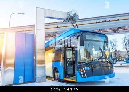 Stazione di ricarica elettrica ad alta tensione per la ricarica degli autobus elettrici alla fermata finale del percorso cittadino. Autobus alla fermata finale con porta aperta Foto Stock