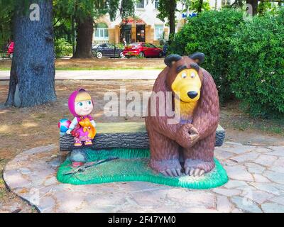 Russia, Sochi 28.06.2020.statue di personaggi fiabeschi Masha e l'orso siedono su una panchina fatta di tronchi nel parco Foto Stock