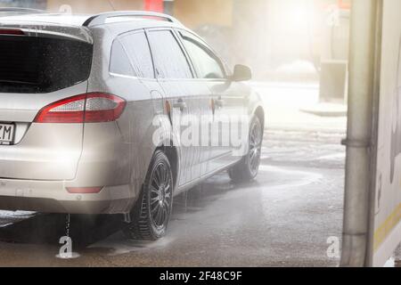 Vista posteriore di un'auto argentata lavata con acqua e sapone in carwash Foto Stock