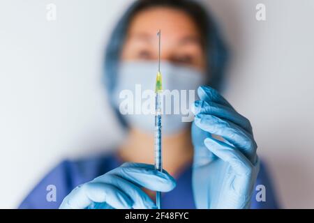 Le mani di un'infermiera con una siringa in mano sono gugorate chirurgicamente. Foto Stock