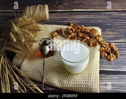 Cibo sano con latte, noci e miele. Aprire il vaso di miele e un cucchiaio su un tovagliolo. Foto Stock