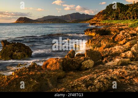 Tramonto spettacolare a Paradise Cove, onde dell'Oceano Pacifico che si infrangono su rocce vulcaniche lungo la costa idilliaca, Kapolei, Oahu, Hawaii, USA Foto Stock