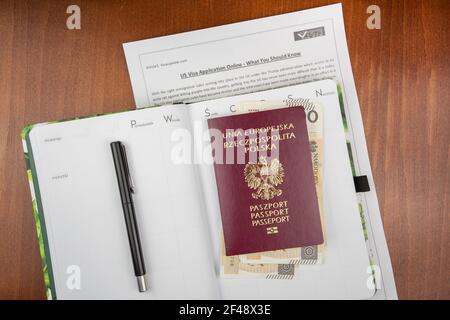 Vista dall'alto del passaporto rosso polacco con banconote e documenti sulla superficie di legno Foto Stock