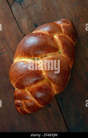 Pane dolce di Pasqua, brioche intrecciata, tsoureki, sfidante. Pagnotta su sfondo tavolo in legno, vista dall'alto verticale. Dolce religioso tradizionale festivo Foto Stock