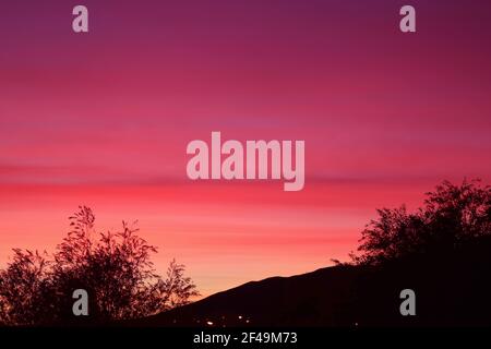 Cielo mozzafiato al tramonto con luce viola sfumata sulla silhouette di montagna Foto Stock