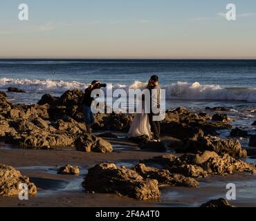 Malibu, CA USA - 1 marzo 2021: Vista ravvicinata di un fotografo che scatta foto di una coppia appena sposata sulla spiaggia di El Matador Foto Stock