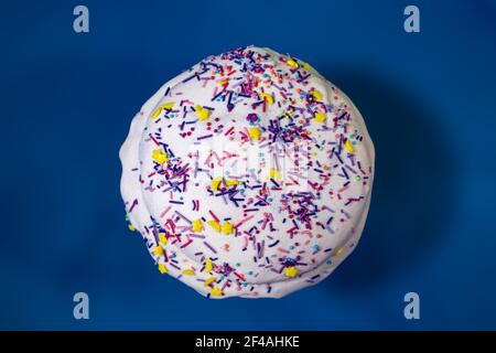 Vacanze di Pasqua pane dolce isolato, paska decorato con zucchero a velo su sfondo blu vista dall'alto. Kulich ortodosso tradizionale colorato fatto a mano con Foto Stock
