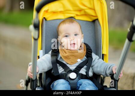 Bambino dolce seduto in un passeggino all'aperto. Bambino piccolo in pRAM. Bambino in passeggino. Passeggiate estive con i bambini. Vacanza in famiglia con bambino piccolo Foto Stock