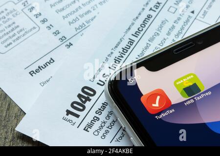 Le icone dell'app mobile TurboTax e HRB Tax Prep vengono visualizzate su un iPhone, con il modulo 1040, il rendimento delle imposte sul reddito individuale degli Stati Uniti, sullo sfondo. Foto Stock