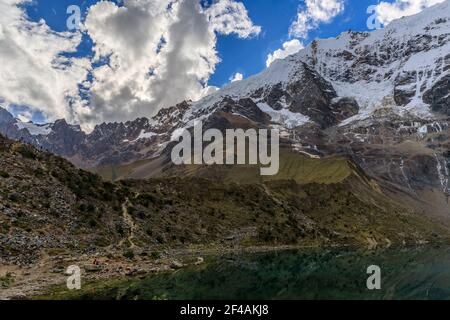 Cielo soleggiato con belle nuvole bianche che si affaccia sulla neve La catena montuosa e la cima del Salkantay e le fredde acque blu Del lago Humantay in Perù Foto Stock