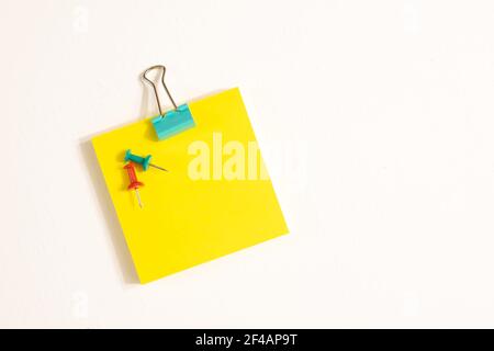 Fermagli per rilegatori verdi, perni e note adesive gialle isolati su sfondo bianco. Concetto di scuola e business Foto Stock