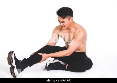 l'uomo di idoneità del muscolo che raggiunge per la sua gamba nel dolore Foto Stock