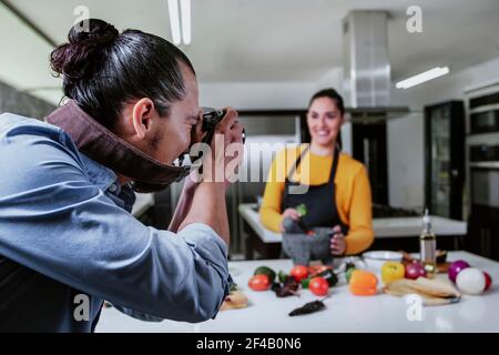 donna latina cibo Blogger tiro cibo sul tavolo, mentre un fotografo uomo sta scattando foto con la macchina fotografica del cibo messicano in cucina a città del messico Foto Stock