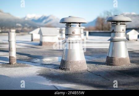 Set di ventilatori a tetto piatto su edificio con sistema di copertura in bitume modificato. Gruppo di differenti aperture di metallo di forma come: Bagni e lavanderia ex Foto Stock