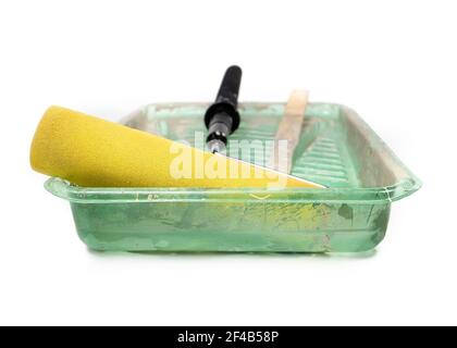 Rullo e teglia usati e puliti. Vista frontale del grande rullo in schiuma giallo grossolano nel vassoio di plastica verde con strati di vernice attaccati. Concetto per il fai da te Foto Stock
