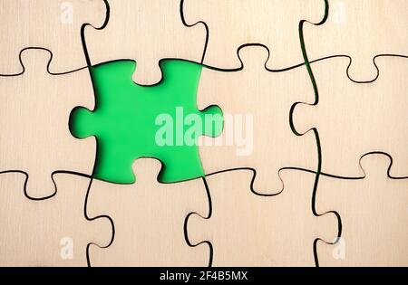 Pezzo di puzzle mancante. Quasi finito, grande puzzle fatto di legno su sfondo verde. Concetto per andare avanti, capire un processo. Foto Stock