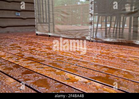 L'acqua perda su un ponte di legno appena sigillato dopo una tempesta mattutina al cottage. Foto Stock