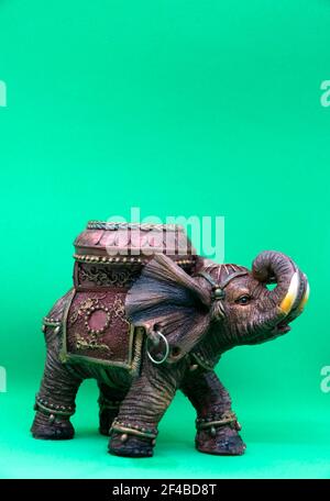 Figurine di un elefante indiano su uno sfondo verde primo piano. Candelabro a forma di elefante indiano. Foto Stock