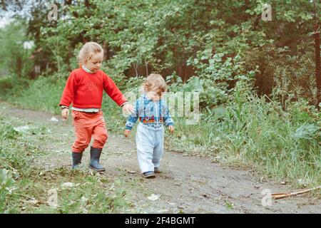 sorella e fratello camminano per la strada in un piccolo villaggio tra le case Foto Stock