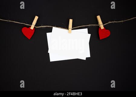 Busta e cuori rossi, appesi in linea su sfondo nero. Decorazione San Valentino. Foto Stock