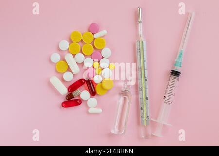 Flacone di vetro con medicinali. Termometro, siringa e pillola per il trattamento dei raffreddori su sfondo rosa. Rimedi a freddo. Concetti medici e medicinali. Via superiore Foto Stock