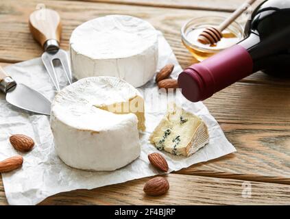 Vari tipi di formaggio, formaggio blu, bree, camambert e vino su un tavolo di legno Foto Stock