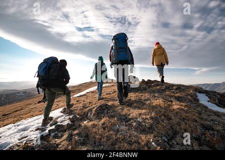 Gruppo di quattro turisti diversi o escursionisti sono a piedi cima della montagna all'ora del tramonto Foto Stock
