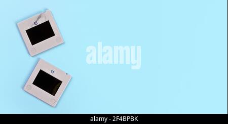 Due diapositive fotografiche diapositive sul tavolo blu chiaro, vista dall'alto, spazio per testo lato destro - concetto di fotografia retrò Foto Stock