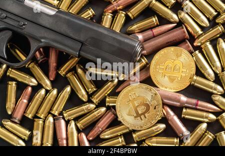 Proiettili in bronzo e ottone sparsi su tavolo scuro, canna nera pistola, monete d'oro bitcoin vicino - uso illegale di criptovaluta per l'acquisto di armi Foto Stock