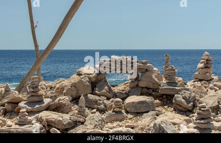 Sculture di ciottoli marini contro il mare blu e il cielo limpido. Scultura di ciottoli realizzata sulla spiaggia adriatica. Foto Stock