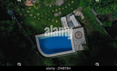 AEREO Top Down Tiro di un lussuoso hotel giungla territorio con piscina a Bali, Indonesia. Drone si trova in su Foto Stock