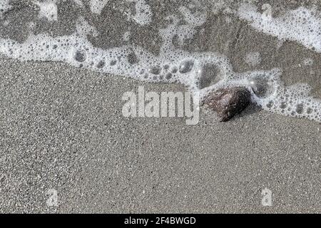 Onde morbide sulla spiaggia di sabbia vulcanica nera. Sfondo con spazio di copia. Foto Stock